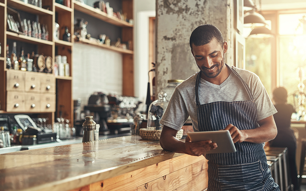 Happy male owner of cafe using digital tablet