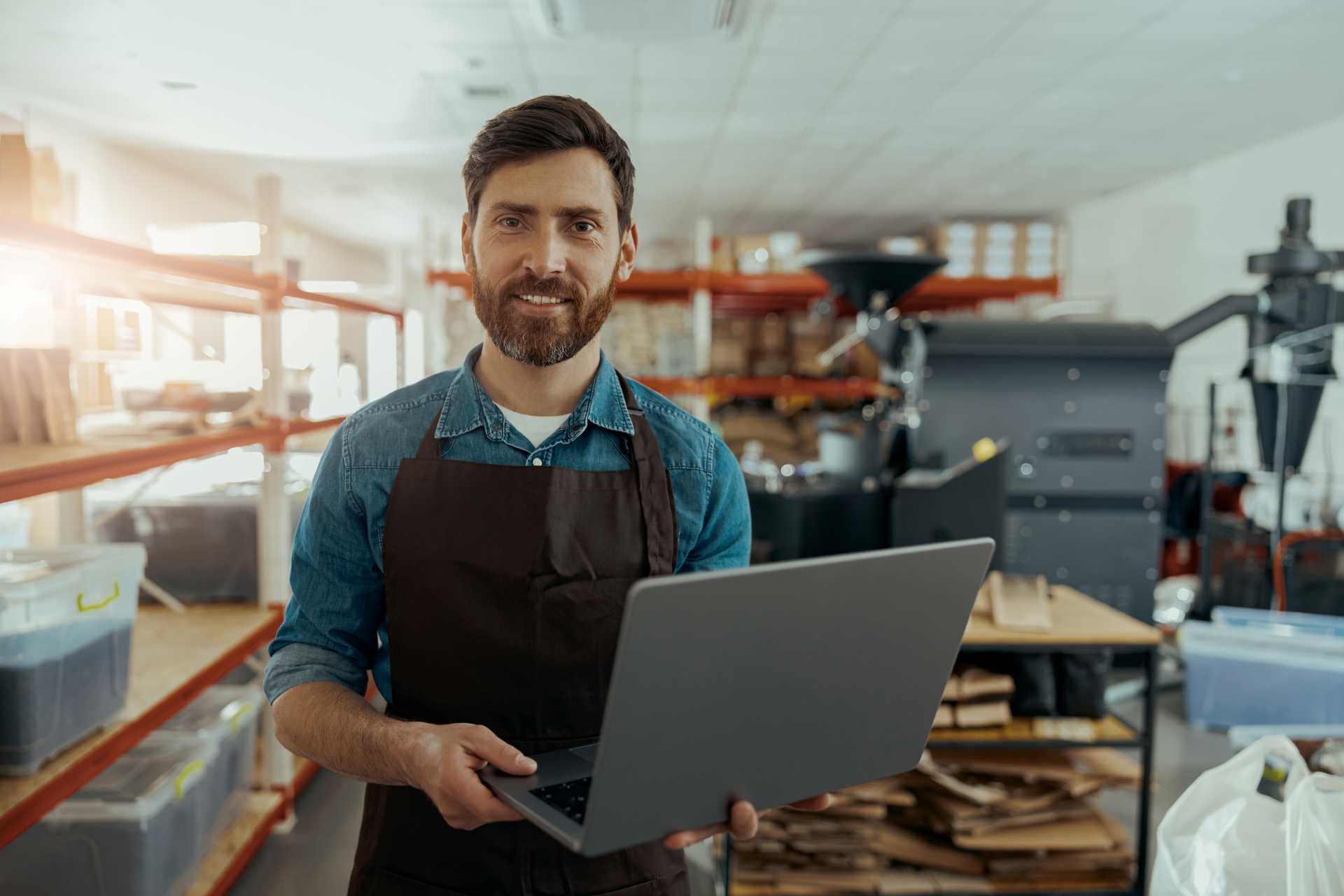 business central add-ons, A smiling small business owner holding a laptop in a warehouse.