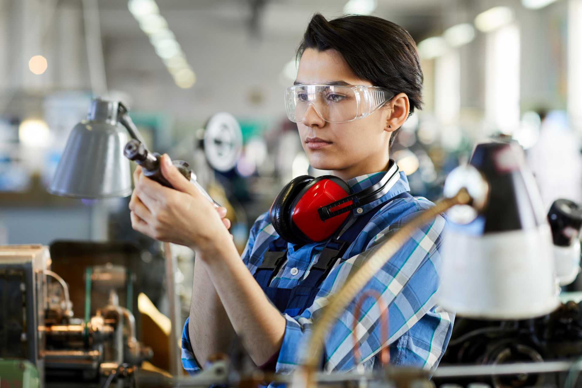 ERP for manufacturing efficiency, a worker is inspecting metal parts in a factory setup.