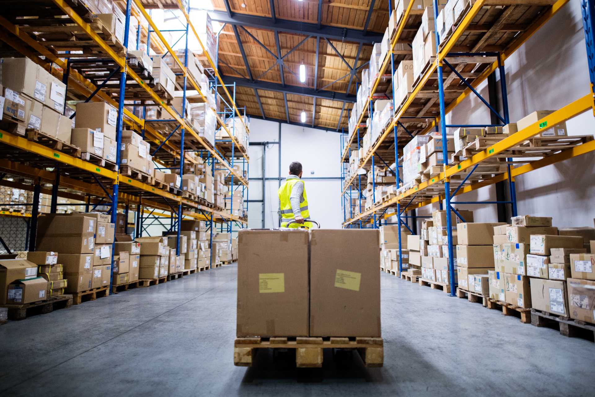 outgrowing spreadsheets in a growing business, A warehouse worker pulling pallet with delivery boxes